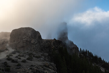 trail to roque nublo rock in clouds at sunset over the mountains