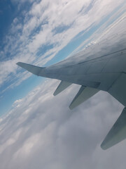 Fototapeta na wymiar wing of airplane climbing above clouds, tilted horizon, view from porthole
