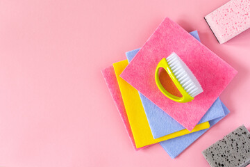 Multi-colored cloths and cleaning sponges on pink background