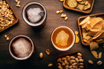 Different types of drink, chips, croutons and nuts in plates and scattered on table