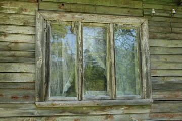 Window of an old abandoned wooden house in the Latvian village of Kemeri in May 2020