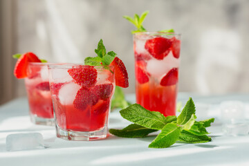 Glass of strawberry soda drink on light blue background. Summer healthy detox lemonade, cocktail or another drink background. Nonalcoholic drinks, vegetarian or healthy diet concept.