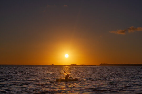 Person kayaking in the middle of the sea during sunset