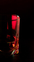 A part of cognac glass in ruby red light with ruby red highlights on the glass wall.