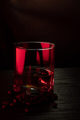 Cognac glass in ruby light with white, amber highlights, grains near the glass.