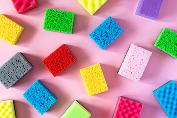 Pattern of multi-colored cleaning sponges on a pink background