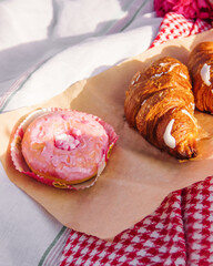 close-up delicious croissant and pink donut lie on a tablecloth. picnic concept, free space