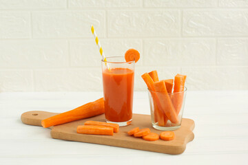 Glass of carrot juice and fresh carrot on cutting board