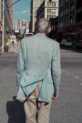 Elderly man waiting in city looking to meet old friend, remembers his youth, wears elegant blue jacket.