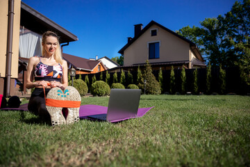 Pretty sportive fitness coach woman using  fitness gum to stretch and watching at laptop.