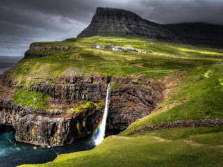 A view on Mulafossur waterfall in Gasadalur, Faroe islands with small rainbow.