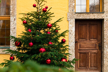 Fototapeta na wymiar Christmas tree winter holidays street urban view background with festive toys and wooden door