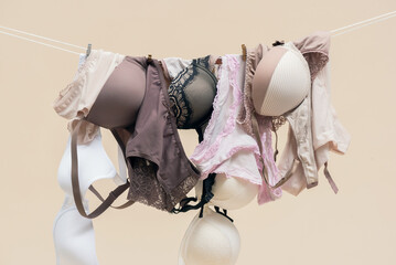 Female bra and panties is hanging on the rope isolated on a light background. - obrazy, fototapety, plakaty