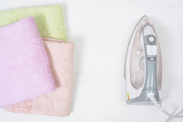 Electric iron and towels on a white flat lay background.