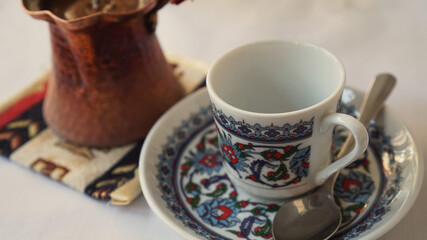Small turkish style coffee cup with a teaspoon on a white table. Eastern cuisine.