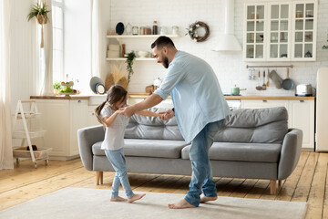 Happy father dancing having fun with little daughter in modern living room. Family playing funny...