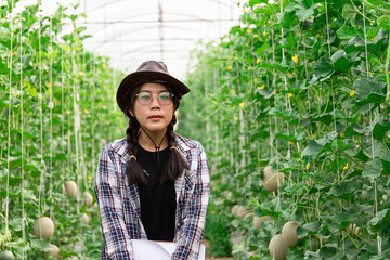 smart farmer using technology in an agriculture field, She was watching the produce from her garden, her checking by using notebook in farm field.