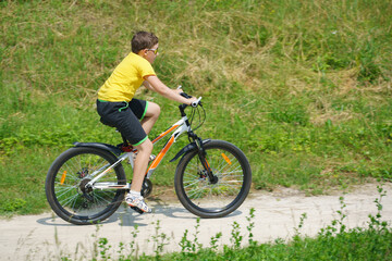 Obraz premium The boy rides a bicycle in the park