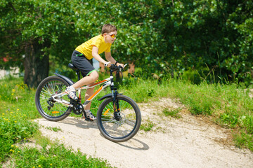 Fototapeta na wymiar The boy is rolling downhill on a bicycle