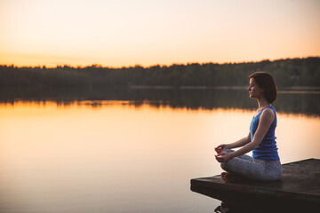  Woman exercising yoga pose vital and meditation for fitness lifestyle outside. sunrise on lake. nature background. Healthy and Yoga Concept. Peaceful lifestyle. copy space