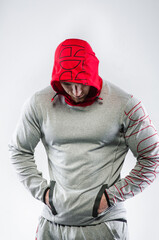 Fototapeta na wymiar A sporty guy stands in the Studio on a white background in a hood. Sports, beauty