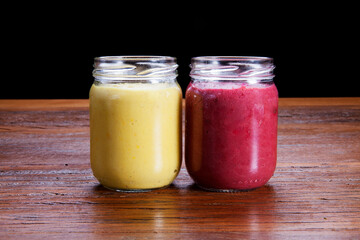 Two glass jars of homemade soup over a wooden table
