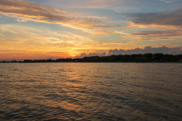 Fototapeta premium View of the water at Lake Neusiedl in Podersdorf, Austria. In the background is a dramatic sky at sunrise.