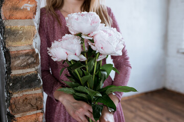 pink flowers in the hands of a girl in a pink dress, peonies surprise for the holiday