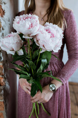 pink flowers in the hands of a girl in a pink dress, peonies surprise for the holiday