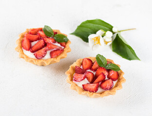 Dessert tartlets with vanilla cream and fresh strawberries on a white background