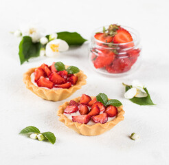 Tartlets with custard and fresh strawberries on a light background