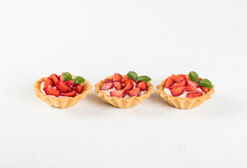 Dessert tartlets with cream and strawberries on a white background 