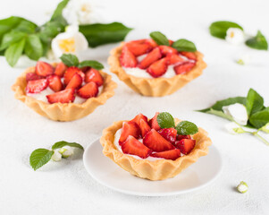 Dessert tartlets with vanilla cream and strawberries on a white background