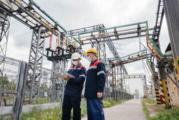 Engineers electrical substations conduct a survey of modern high-voltage equipment in the mask at the time of pandemia. Energy. Industry