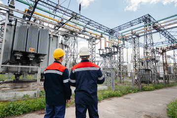 Two specialist electrical substation engineers inspect modern high-voltage equipment. Energy. Industry - obrazy, fototapety, plakaty