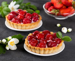 Tartlets with custard and fresh strawberries on a dark gray background
