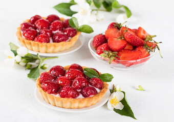 Tartlets with custard milk-yolk cream and fresh strawberries on a light background