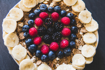 Cereals and fruits superbowl, healthy bowl breakfast with flakes, oat and fruits: raspberries, blueberries, banana, blackberries