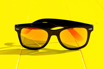 daylight. bright sun. Clear shadows. Wooden background in yellow. He is wearing sunglasses