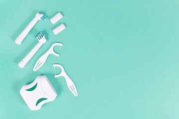 Dental care flat lay with electric toothbrush heads, floss and chewing gum on mint colored...