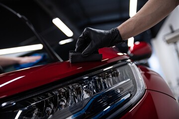 Obraz na płótnie Canvas Man worker of car detailing studio applying ceramic coating on car paint with sponge applicator.