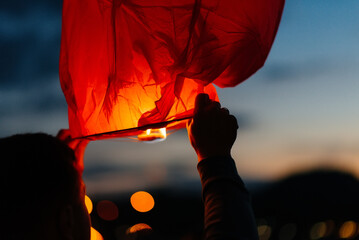 The child starts the lanterns into the sky on a dark night. Celebration, traditions of the new year. © Andrii