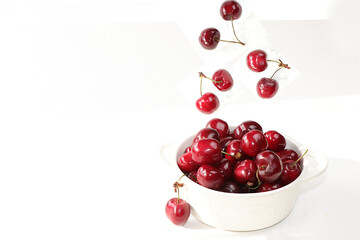 Cherry flying in a white cup on a light table. The concept of healthy and natural food, lifestyle. selective focus