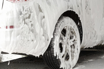 The car is covered with foam at a self-service car wash. Man washes foam machine. Carwash. Washing...