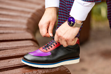 Cropped image of businessman tying his shoe on bench