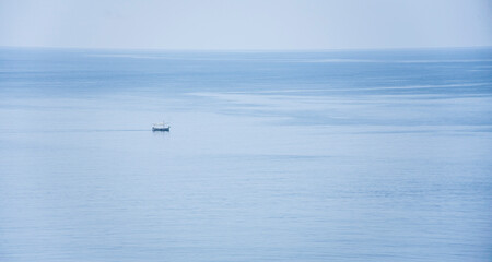 Small calm boat in the middle of the serene sea