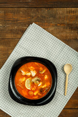 Traditional thai tom yam soup with chicken in a plate with a spoon on a linen napkin.