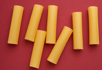raw cannelloni pasta on a red background