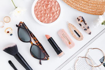 Fashion glasses, lipstick, hair clips, highlighter and magazine flat lay in white background