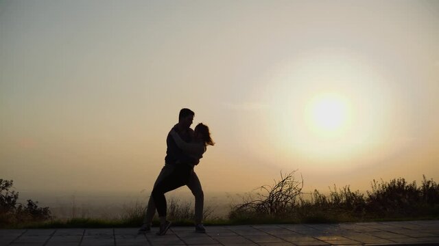 Young couple dancing Latin dance in street at sunset